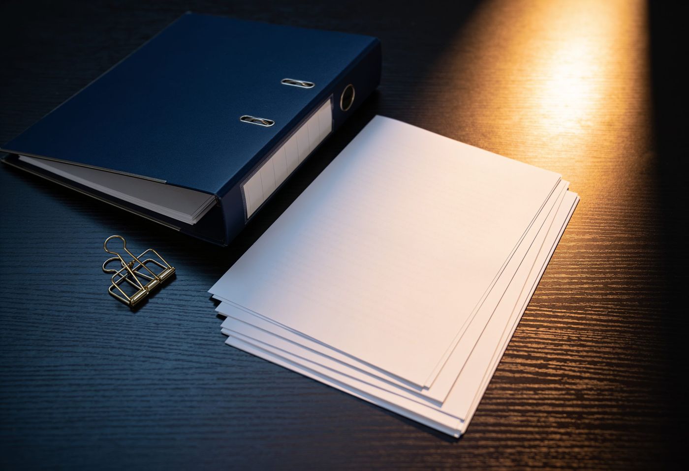 Blank documents gathered into one neat stack on a walnut desk