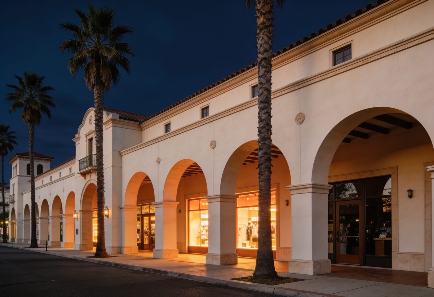 A quiet street in Boca Raton at dusk with arched loggias and royal palms