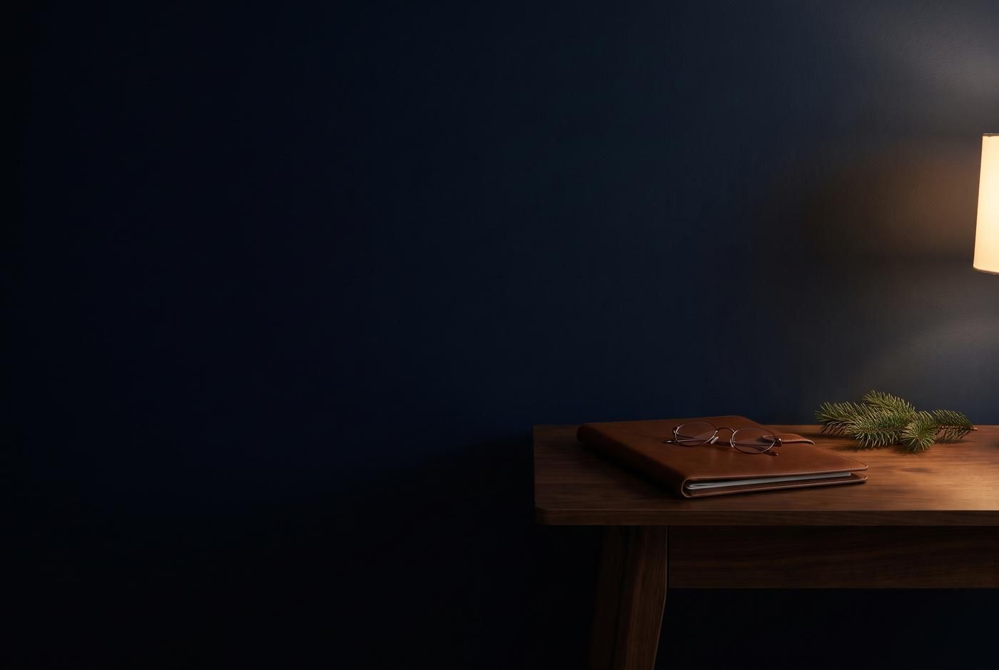 A leather folio and reading glasses on a small table in a dark navy room